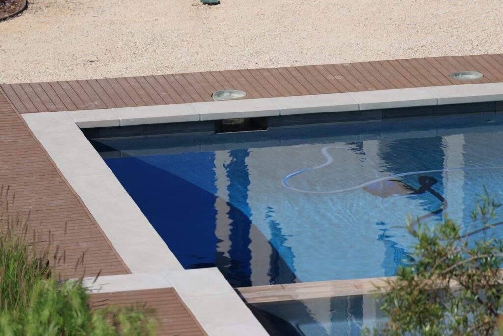 pexels photo 17410701 A serene swimming pool with wooden decking and clear blue water on a sunny day.