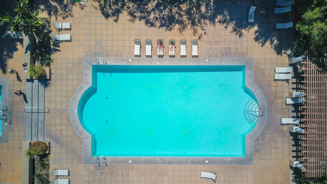 Top-down shot of a swimming pool with sun loungers, perfect for summer relaxation.