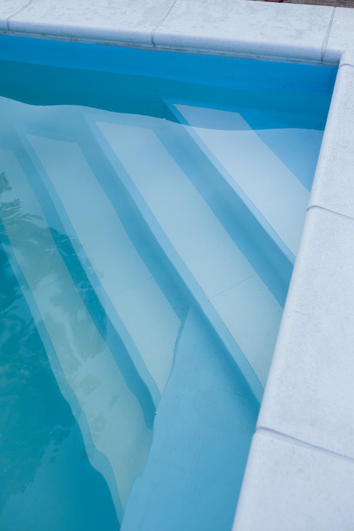 Captured view of pristine swimming pool steps with clear, tranquil blue water.